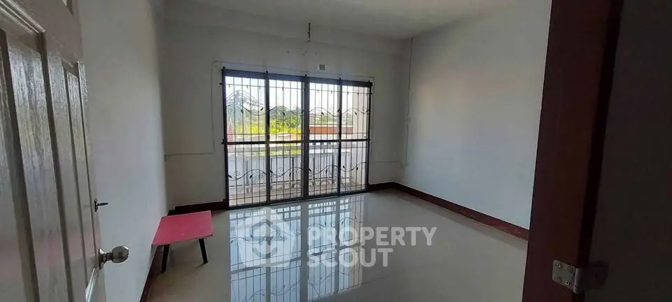Spacious empty room with large window and balcony view, perfect for customization.
