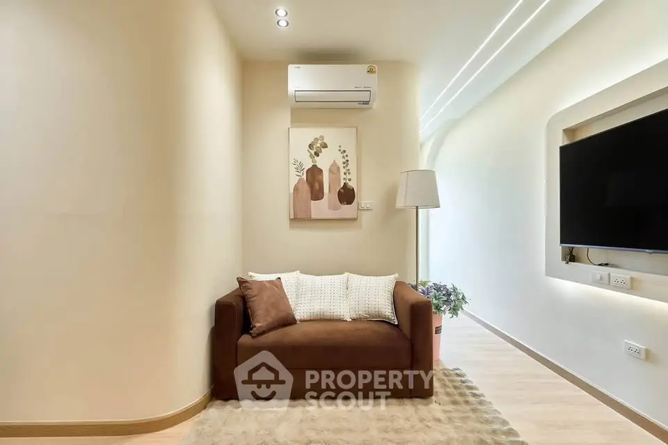 Cozy living room with modern decor, featuring a plush sofa, wall-mounted TV, and elegant lighting.