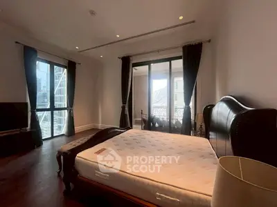 Luxurious bedroom with elegant decor and city view balcony in high-rise apartment.