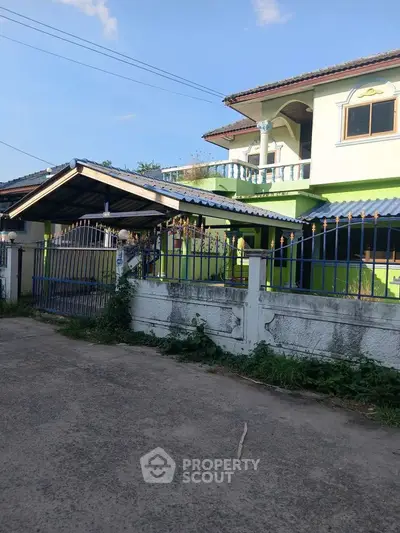Charming two-story house with gated entrance and lush greenery, perfect for family living.