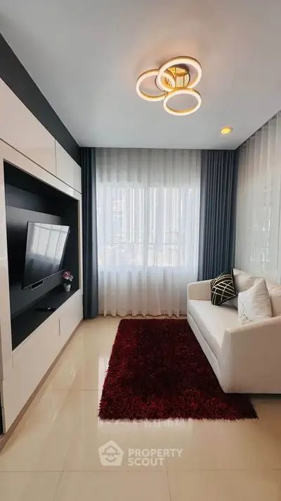 Modern living room with sleek design, featuring a cozy white sofa, built-in TV unit, and elegant lighting.