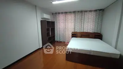 Spacious bedroom with wooden flooring and large window for natural light