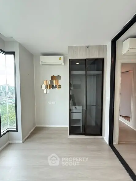 Modern apartment interior with large windows and sleek design, featuring air conditioning and stylish wall decor.